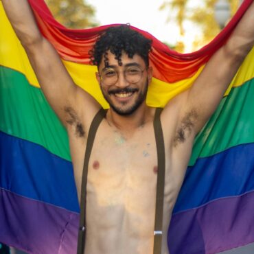 Mann hält Regenbogenflagge hoch